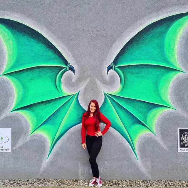 Bettina vor den gezeichnete Drachenflügeln an der Wand